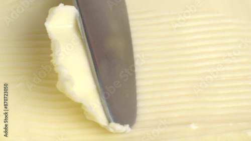 Knife scoops butter, close-up.