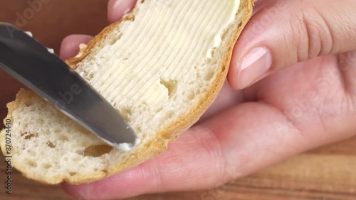 Woman spreading soft butter on slice of bread close up. Spreading cream cheese on bread.