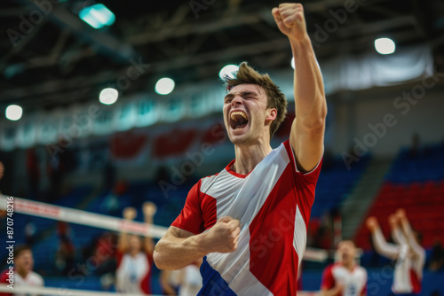 volleyball player celebrates enthusiastically after scoring a crucial point. His teammates in the background share in the excitement, highlighting the joy and camaraderie of the sport.