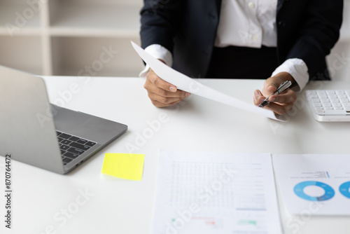 Businesswoman working with documents is analyzing financial data statistically, calculating income and expenses, managing budgets and planning finances. photo