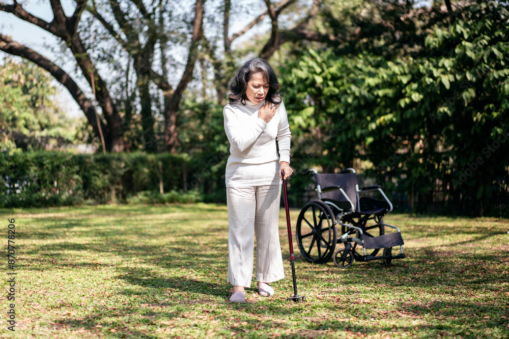 A woman in a white shirt and white pants is walking in a park with a cane A woman in a white shirt and white pants is walking in a park with a cane
