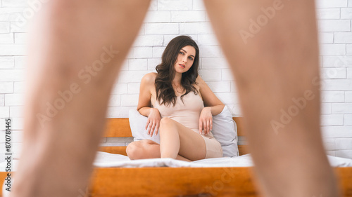 Konstfotografi This image shows a woman sitting on a bed in a white room with a brick wall