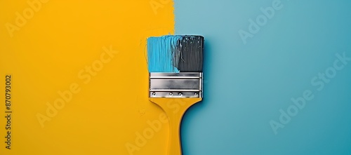 A yellow brush is exposed to blue paint on a yellow and blue background photo