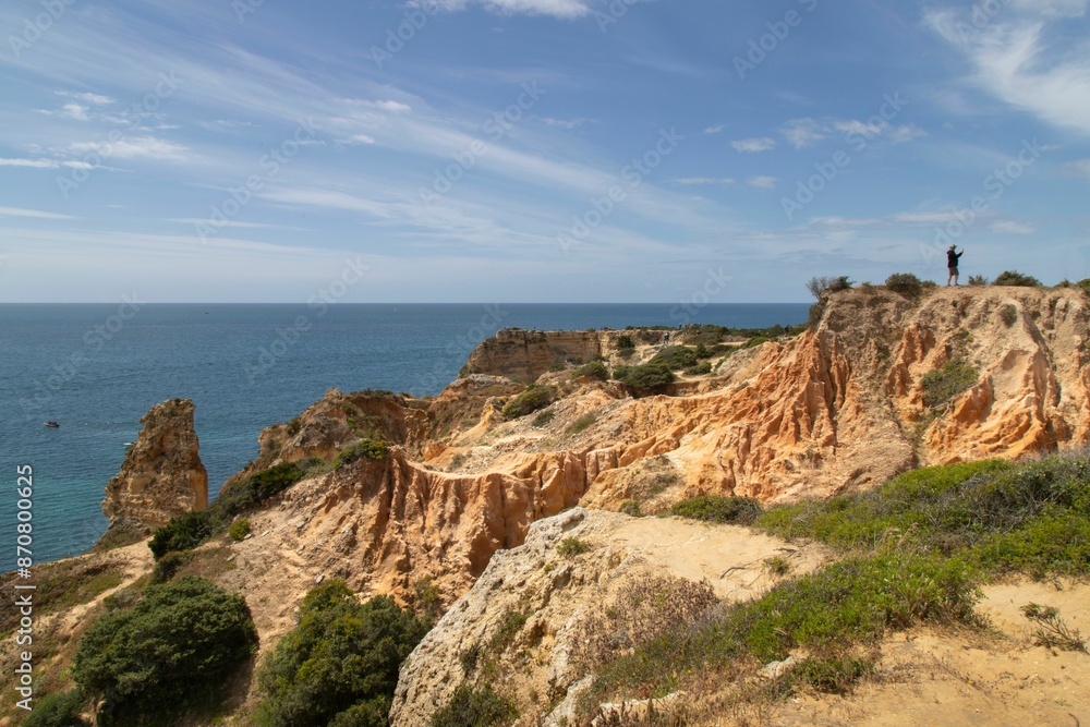 Scenic view of a sandy beach with rocky cliffs and clear blue water in Algarve, Portugal Scenic view of a sandy beach with rocky cliffs and clear blue water in Algarve, Portugal