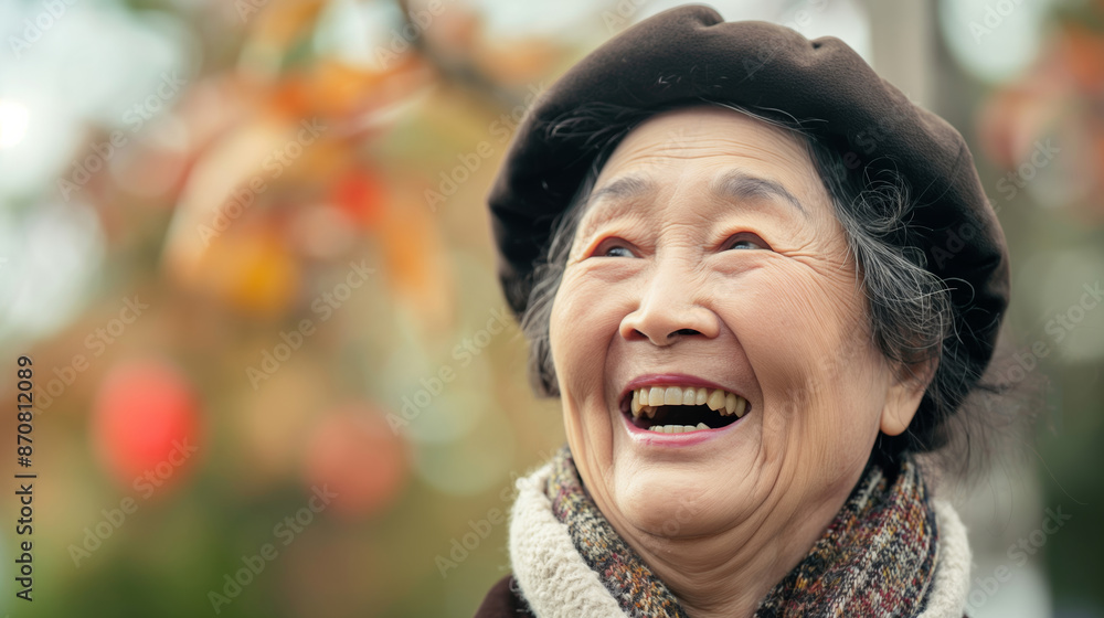 A Asian senior woman with a brown hat and scarf is smiling. She is happy and content. Concept of warmth and happiness A Asian senior woman with a brown hat and scarf is smiling. She is happy and content. Concept of warmth and happiness