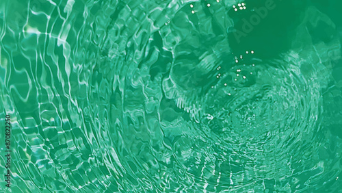 Blue water with ripples on the surface. Defocus blurred transparent blue colored clear calm water surface texture with splashes and bubbles. Water waves with shining pattern texture background.
