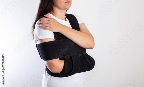 Fotografía A girl in a black medical brace on the shoulder joint for rehabilitation after a fracture of the humerus and dislocation