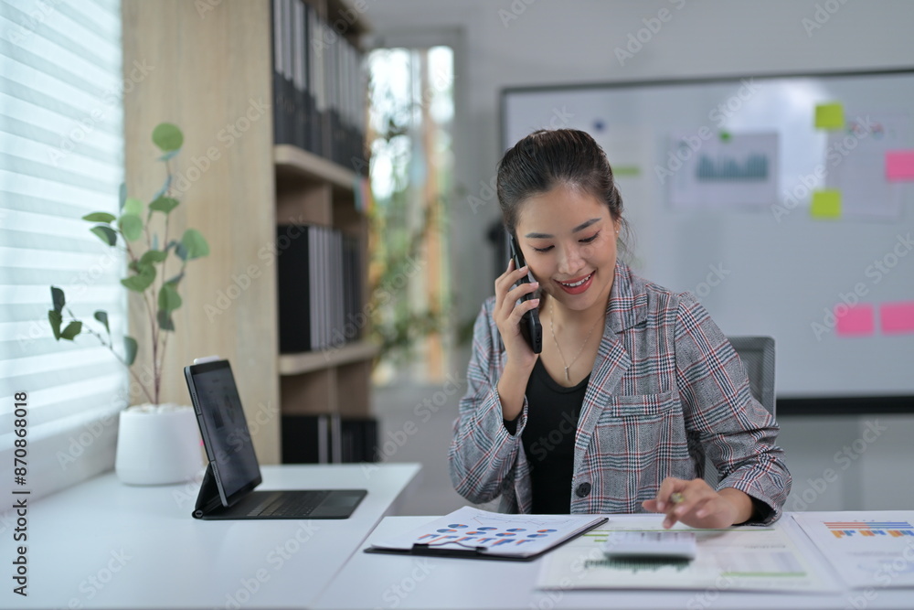 Young Professional Woman Working in Modern Office on Phone Call with Documents and Tablet Young Professional Woman Working in Modern Office on Phone Call with Documents and Tablet