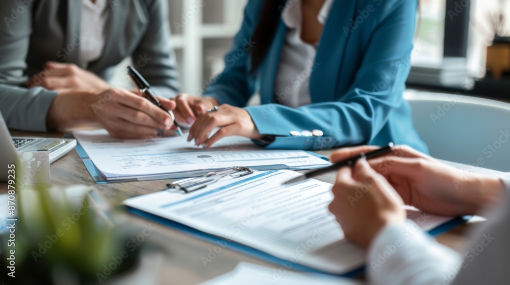 Close-up of business professionals signing documents during a meeting, focusing on hands and paperwork, indicating teamwork and collaboration. Close-up of business professionals signing documents during a meeting, focusing on hands and paperwork, indicating teamwork and collaboration.