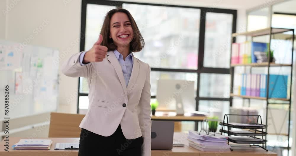 Woman office worker smiles and gives thumbs-up gesture