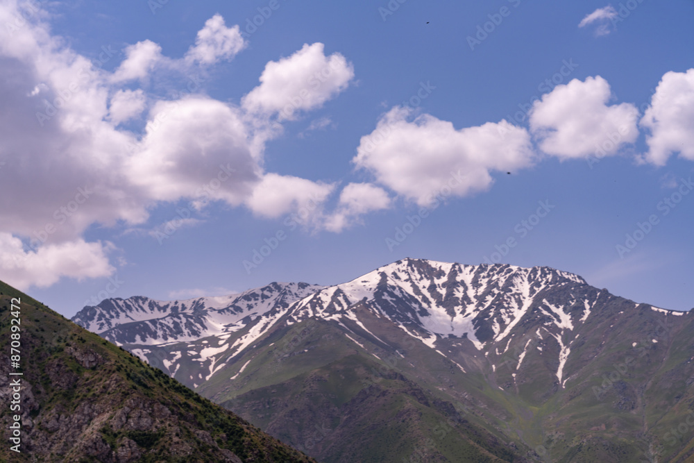 The sky is blue with clouds and the mountains are covered in snow The sky is blue with clouds and the mountains are covered in snow
