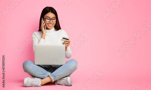 Foto Asian woman sits cross-legged on a pink background