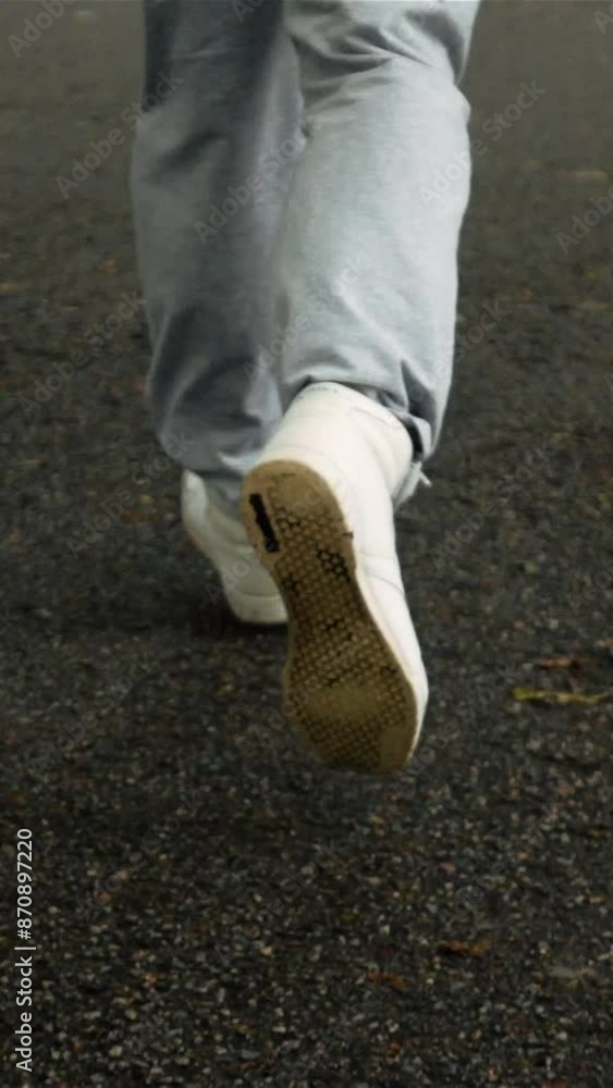 Man legs in sport shoes start to run on asphalt road. Sportsman runner in sneakers running in park. Super slow motion shot. High speed camera steadicam footage. Vertical shot. Man legs in sport shoes start to run on asphalt road. Sportsman runner in sneakers running in park. Super slow motion shot. High speed camera steadicam footage. Vertical shot.