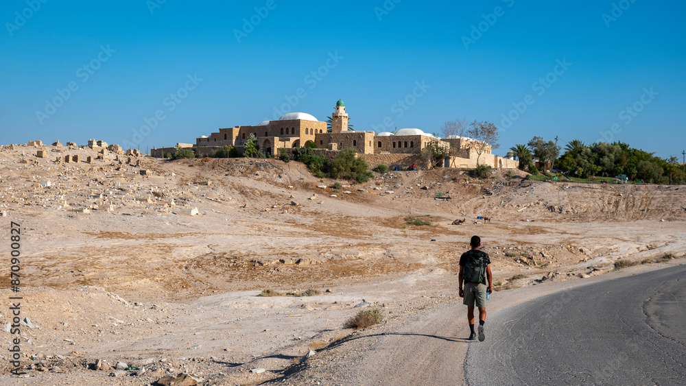 Young Male Explorer Walks Toward An Nabi Musa Mosque and Oasis Garden Seen From Afar