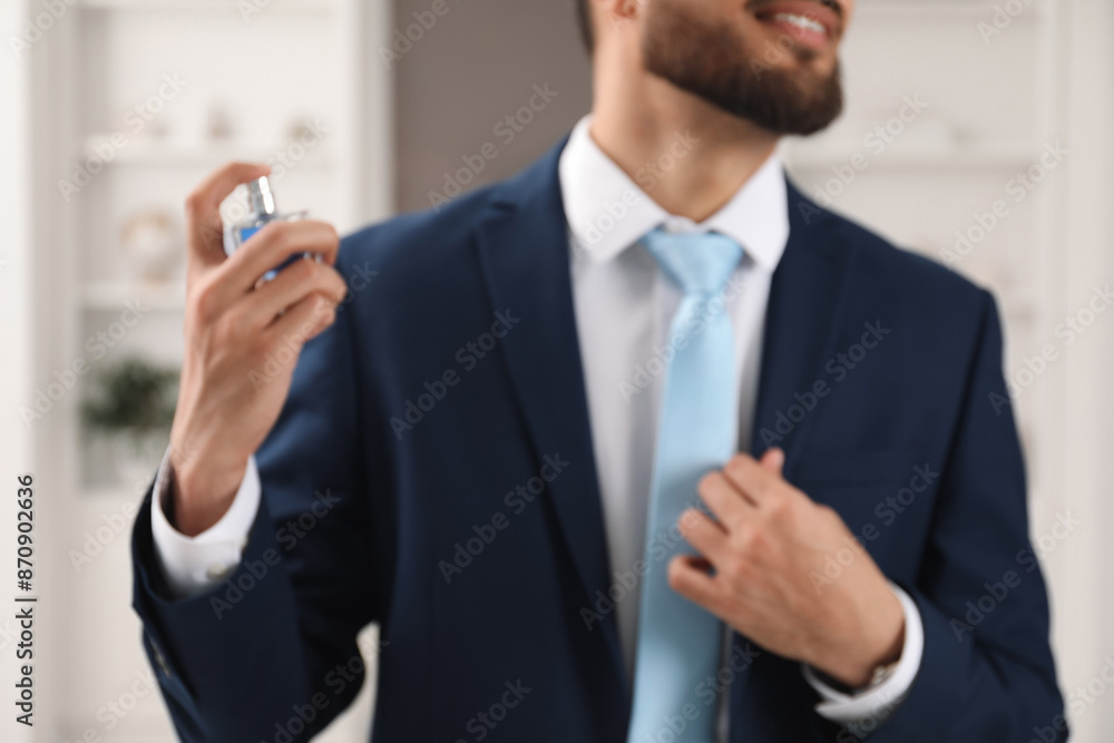 Young man spraying luxury perfume indoors, closeup Young man spraying luxury perfume indoors, closeup