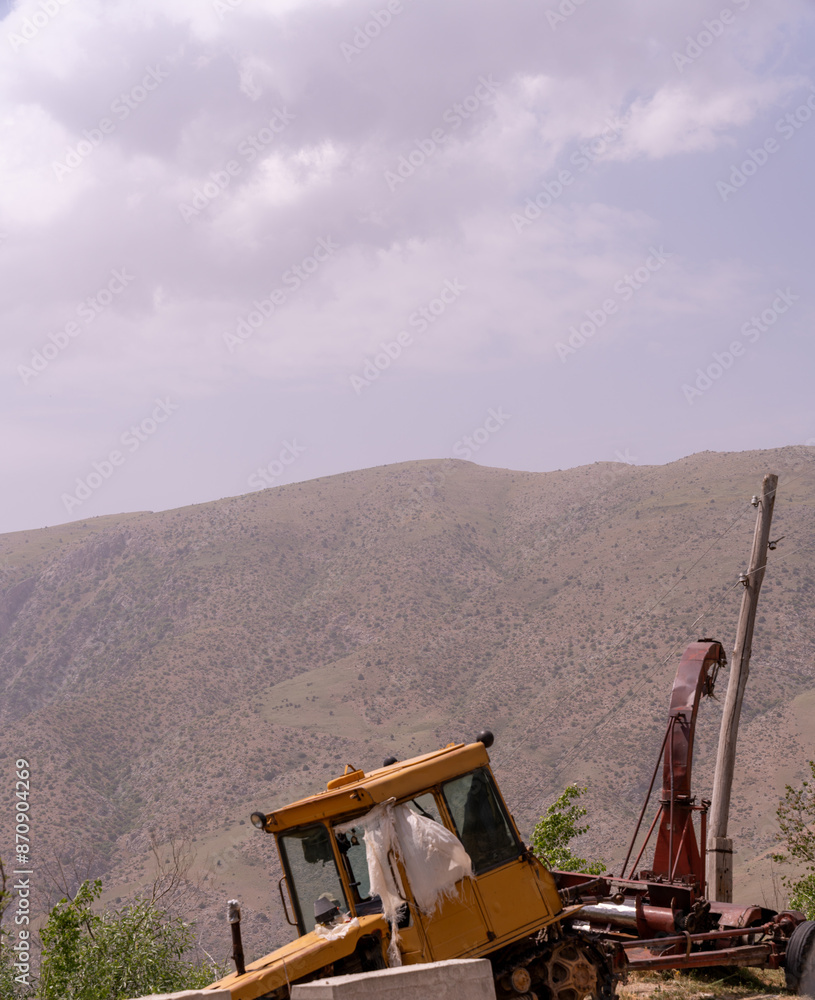 A yellow tractor is sitting on a hillside A yellow tractor is sitting on a hillside