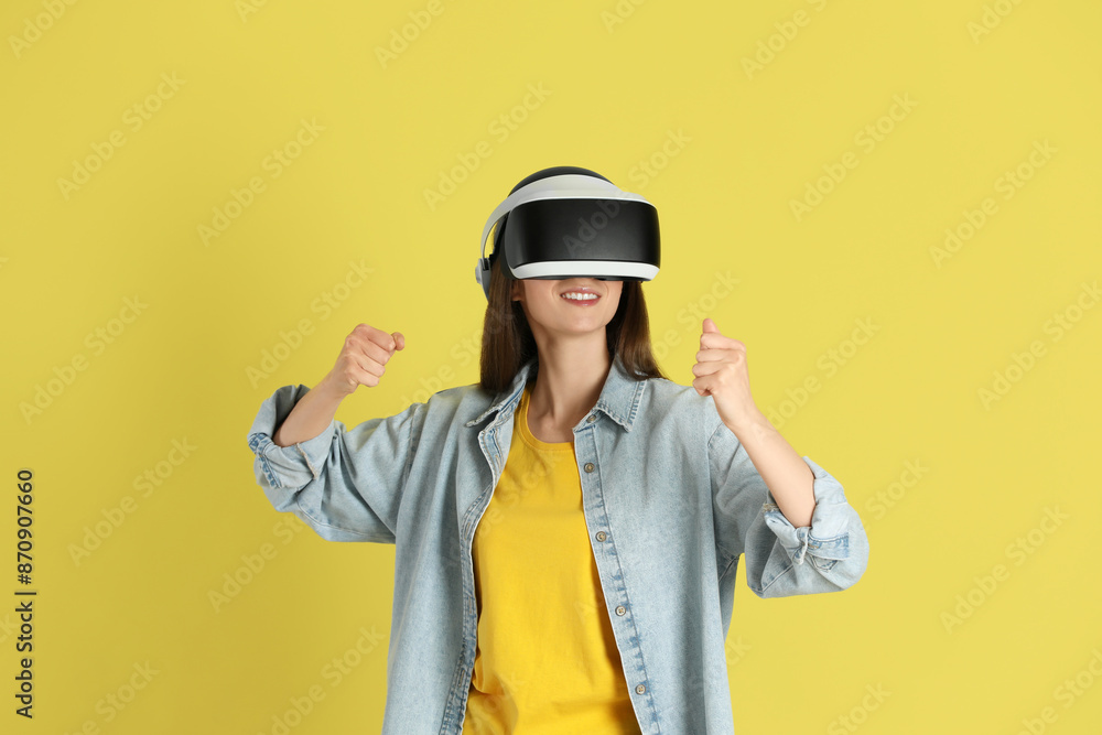 Smiling woman using virtual reality headset on yellow background Smiling woman using virtual reality headset on yellow background