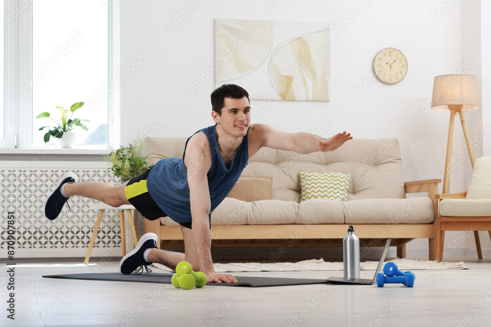 Obraz premium Online fitness trainer. Man doing exercise near laptop at home
