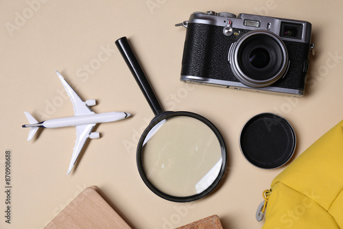 Travel blogger. Flat lay composition with vintage camera and magnifying glass on beige background