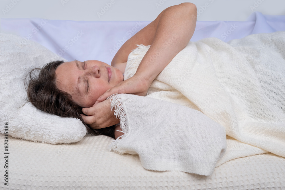 A 50-year-old woman sleeps, covered with white blanket, Healthy Sleep concept, relaxation methods and energy restoration, impact of sleep on mental well-being A 50-year-old woman sleeps, covered with white blanket, Healthy Sleep concept, relaxation methods and energy restoration, impact of sleep on mental well-being