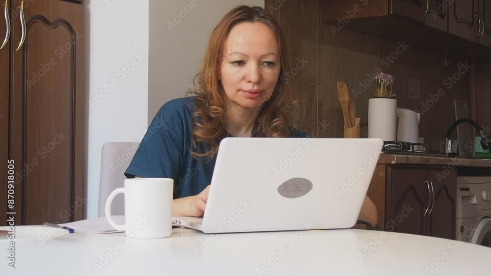 Busy woman eating, drinking coffee, talking on the phone, working on laptop at the same time. Freelancer works at home. woman in the kitchen studying online, talking on video, video call Busy woman eating, drinking coffee, talking on the phone, working on laptop at the same time. Freelancer works at home. woman in the kitchen studying online, talking on video, video call