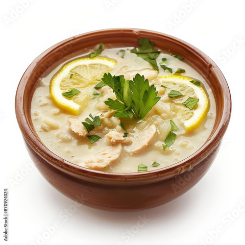 A bowl of Greek kotosoupa, a chicken soup with rice and lemon, garnished with fresh parsley, isolated on white background.