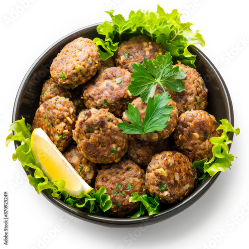 A bowl of Turkish mercimek koftesi, lentil and bulgur patties, served with lettuce leaves and lemon wedges, isolated on white background. photo