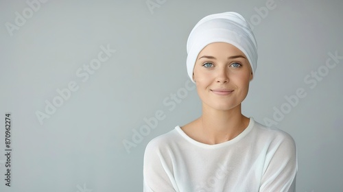 A woman with a gentle smile wearing a white turban against a gray background. photo