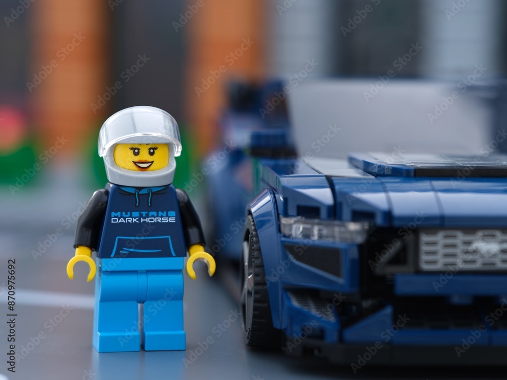 Fototapeta premium Tambov, Russian Federation - July 01, 2024 Lego Ford Mustang Dark Horse sports car driver minifigure standing near her car. LEGO Speed Champions.