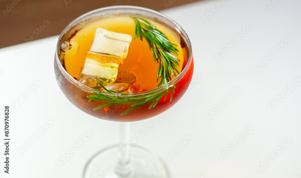 A glass of cocktail with a garnish of rosemary on top A glass of cocktail with a garnish of rosemary on top