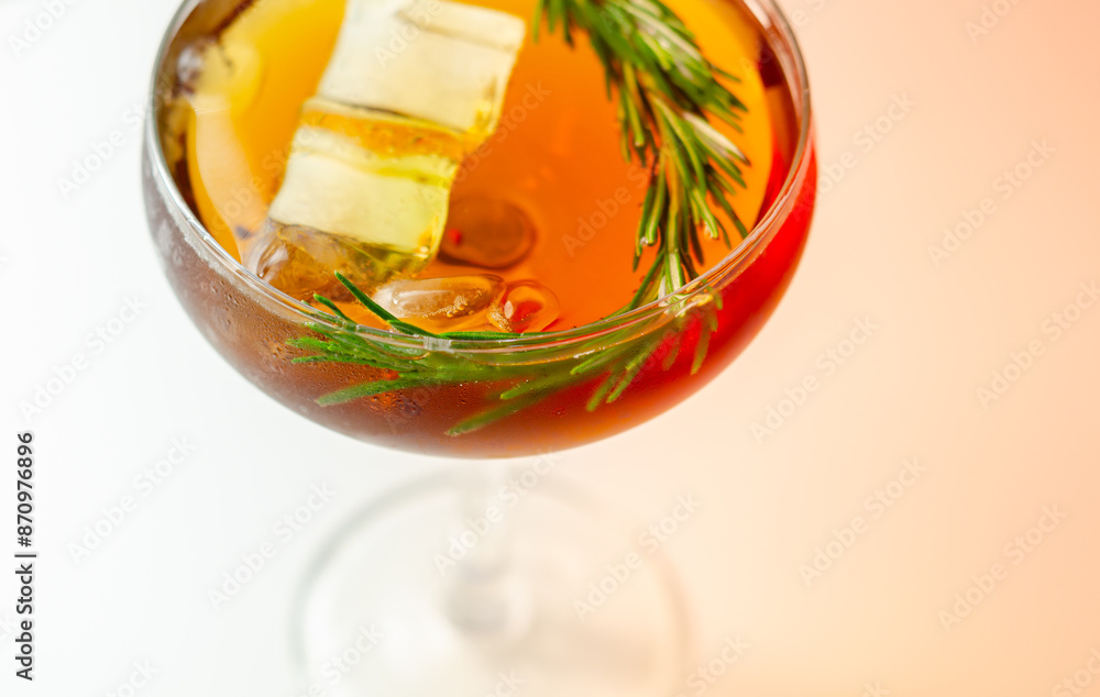 A glass of cocktail with a garnish of rosemary on top A glass of cocktail with a garnish of rosemary on top