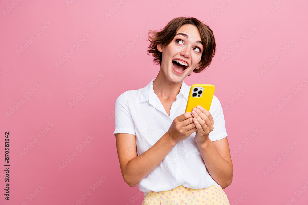 Photo of excited astonished woman with bob hair dressed shirt hold smartphone indicating empty space isolated on pink color background Photo of excited astonished woman with bob hair dressed shirt hold smartphone indicating empty space isolated on pink color background