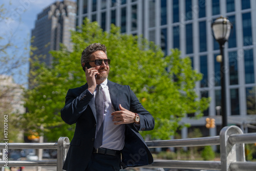 Middle aged Hispanic businessman with phone. Business communication. Business man having phone call outdoor. Businessman using phone. Man phone conversation in suit. Banner © be free