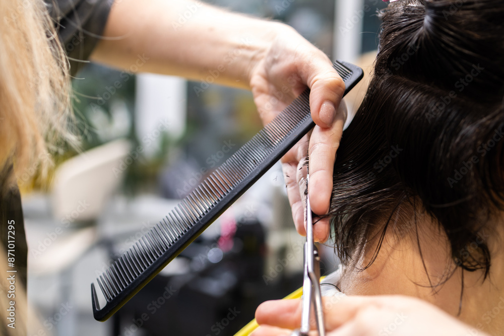 Fototapeta premium Close-up of hair cutting with comb and scissors