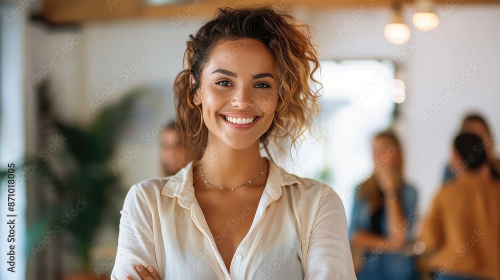 A confident businesswoman smiling brightly in a modern office, portraying professionalism and a welcoming atmosphere. Colleagues are visible in the background, enhancing the lively setting. A confident businesswoman smiling brightly in a modern office, portraying professionalism and a welcoming atmosphere. Colleagues are visible in the background, enhancing the lively setting.