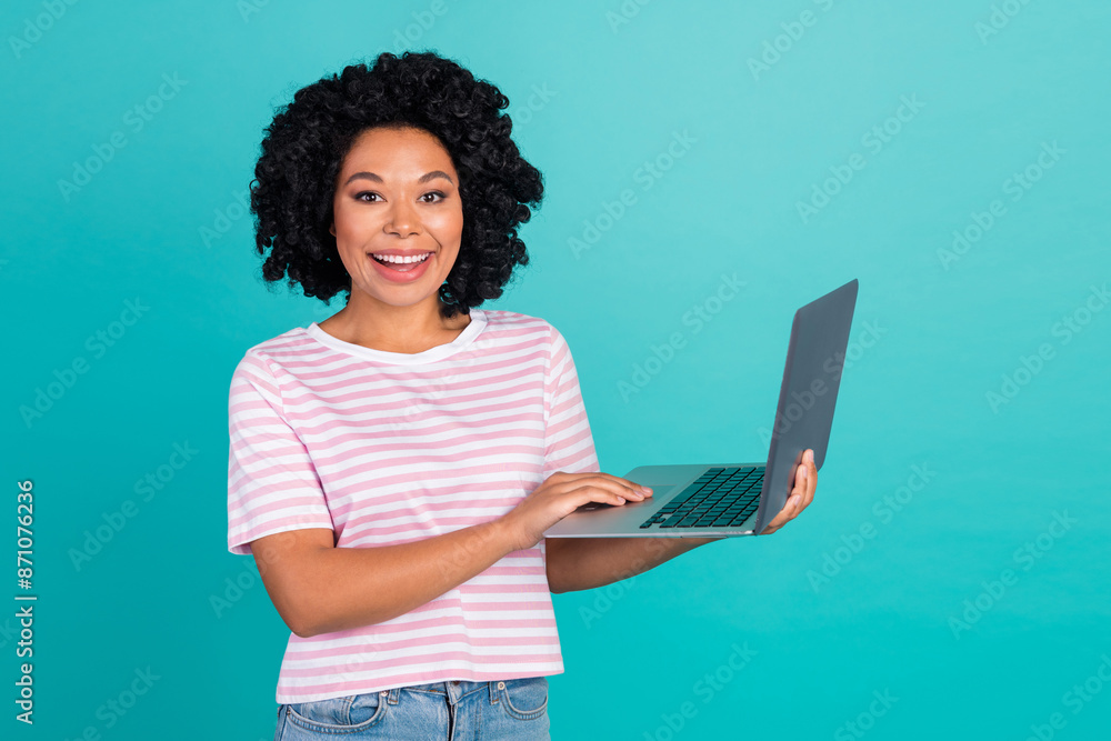 Photo portrait of pretty young girl hold netbook wear trendy striped outfit isolated on aquamarine color background Photo portrait of pretty young girl hold netbook wear trendy striped outfit isolated on aquamarine color background
