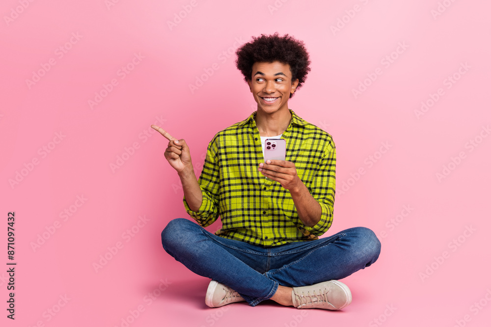 Full size photo of nice young man smart phone direct finger empty space wear shirt isolated on pink color background Full size photo of nice young man smart phone direct finger empty space wear shirt isolated on pink color background