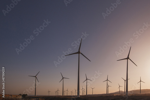 Renewable energy, wind turbines power plant at sunset