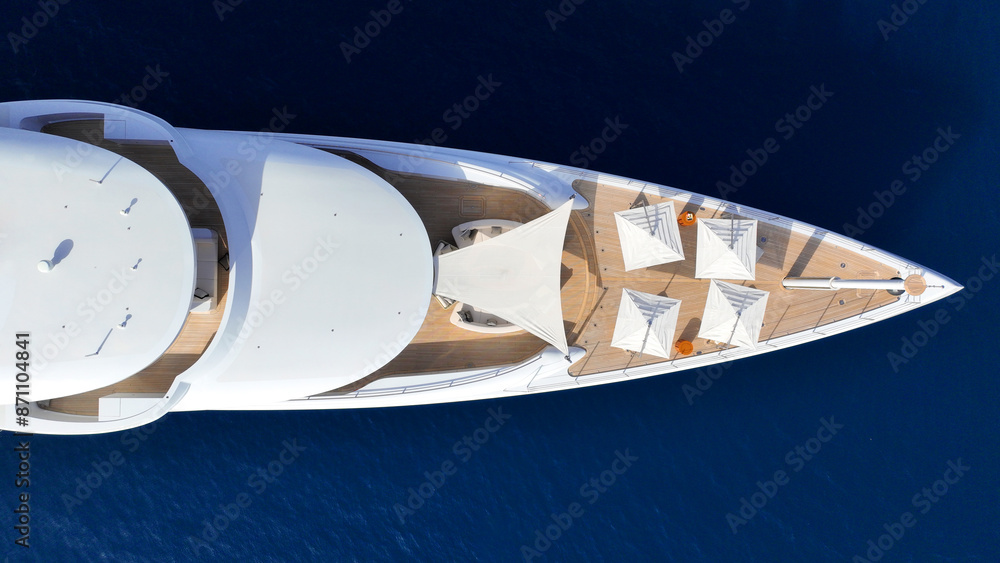 Aerial drone top down photo of luxury super yacht with wooden deck anchored in paradise exotic deep blue sea island bay
