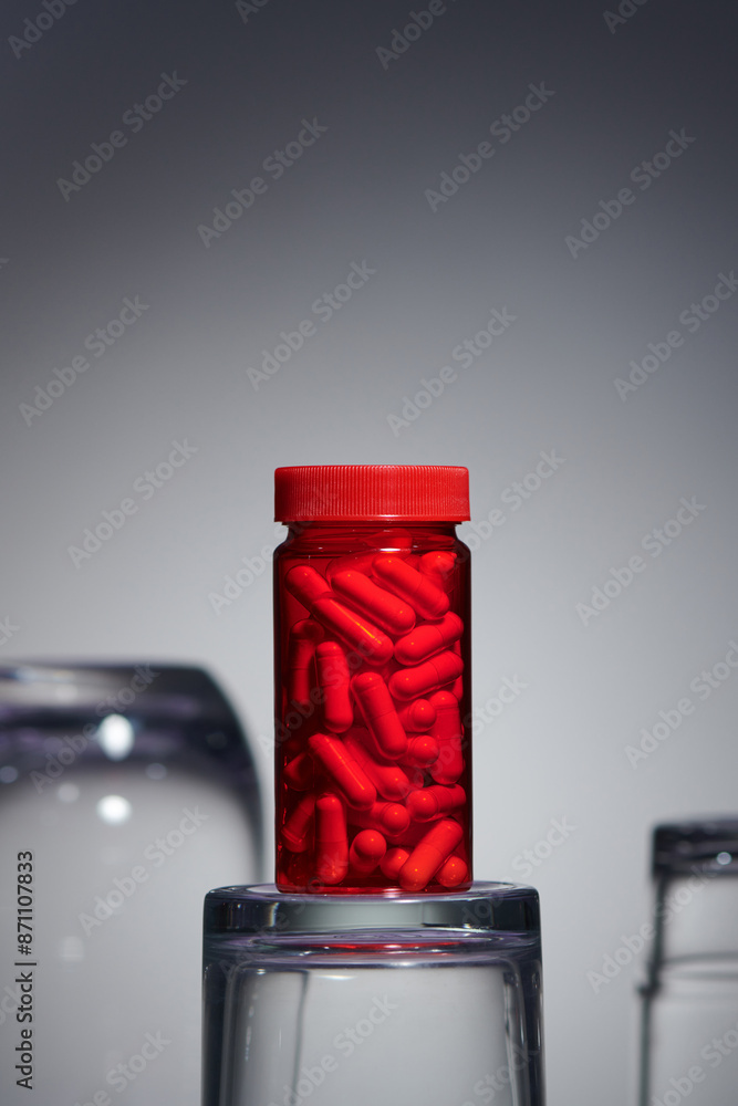 Red bottles transparent with pills capsules on gray background Red bottles transparent with pills capsules on gray background