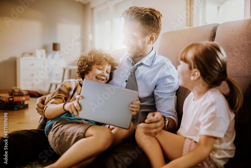 Happy father playing with son and daughter at home