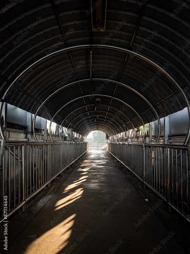 Sun bursts through a rail on a covered pedestrian bridge in Bangkok Sun bursts through a rail on a covered pedestrian bridge in Bangkok