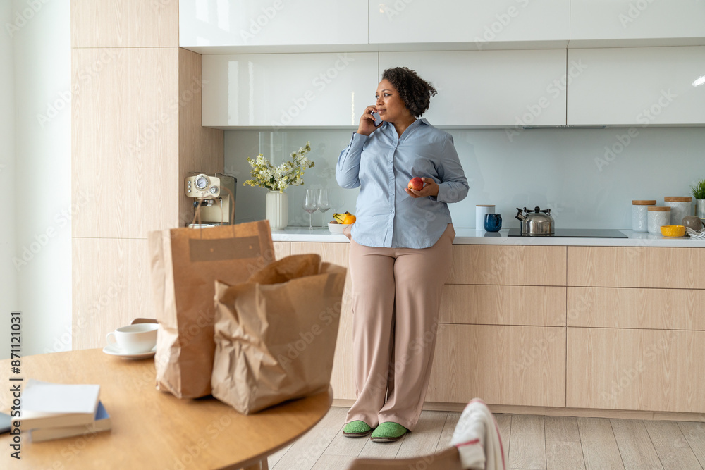 Woman on Phone with Apple in Kitchen Woman on Phone with Apple in Kitchen