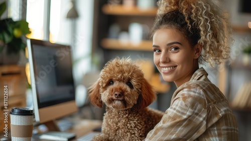 A young lady smiles as she works at her computer with her fluffy dog by her side, creating a stylish and modern home office setting that reflects warmth and companionship. photo