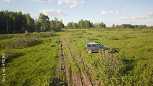 A car prepared for off-road driving and overcoming obstacles against the backdrop of beautiful nature in the rays of the evening sunset.