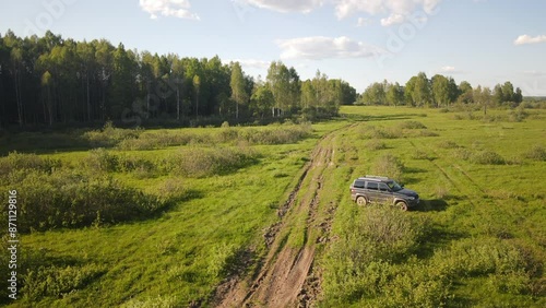 A car prepared for off-road driving and overcoming obstacles against the backdrop of beautiful nature in the rays of the evening sunset.