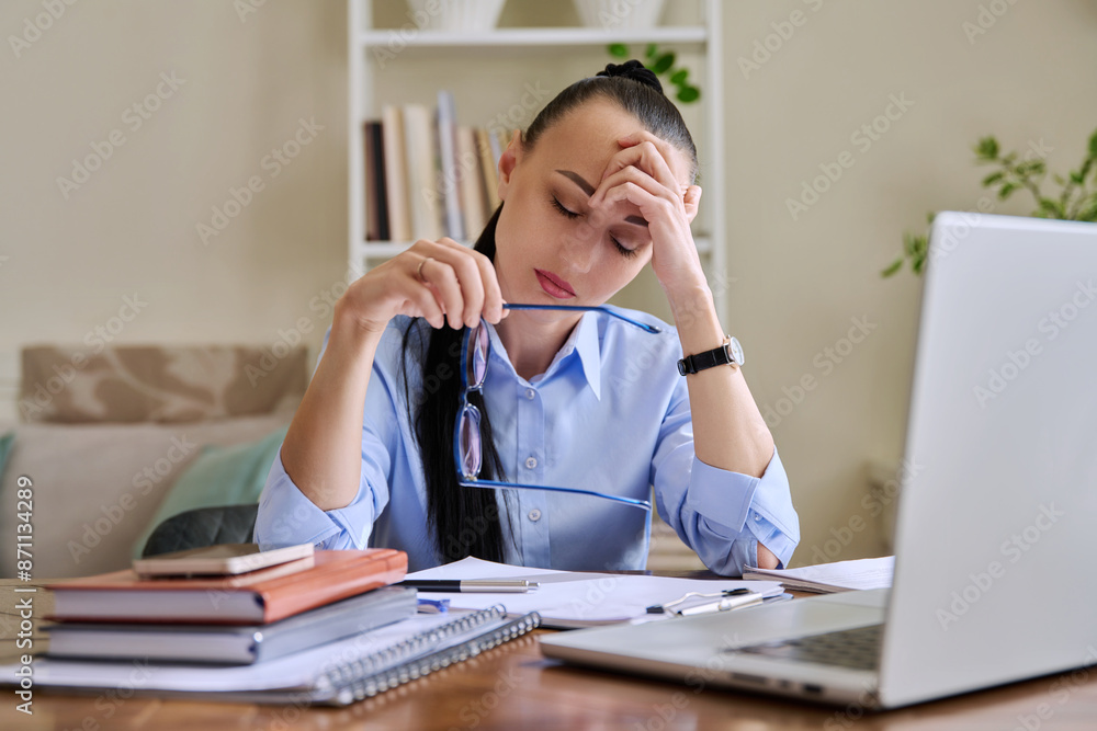 Tired businesswoman having problems sitting at desk with laptop Tired businesswoman having problems sitting at desk with laptop