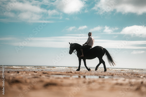 Man riding a horse on a beach, horseback summer cowboy photo