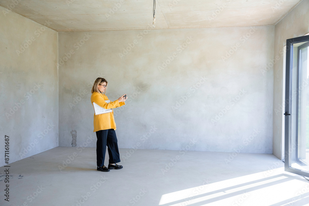 A real estate agent takes pictures on a mobile phone A real estate agent takes pictures on a mobile phone