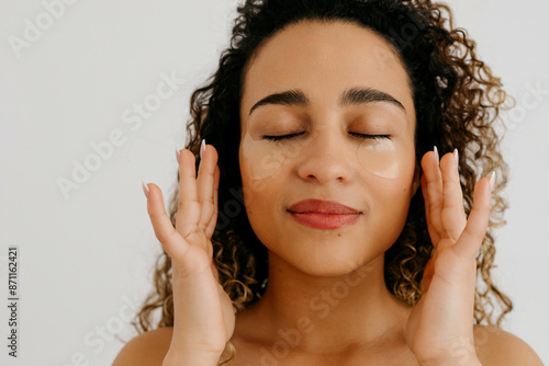 Positive woman applying patches on face photo